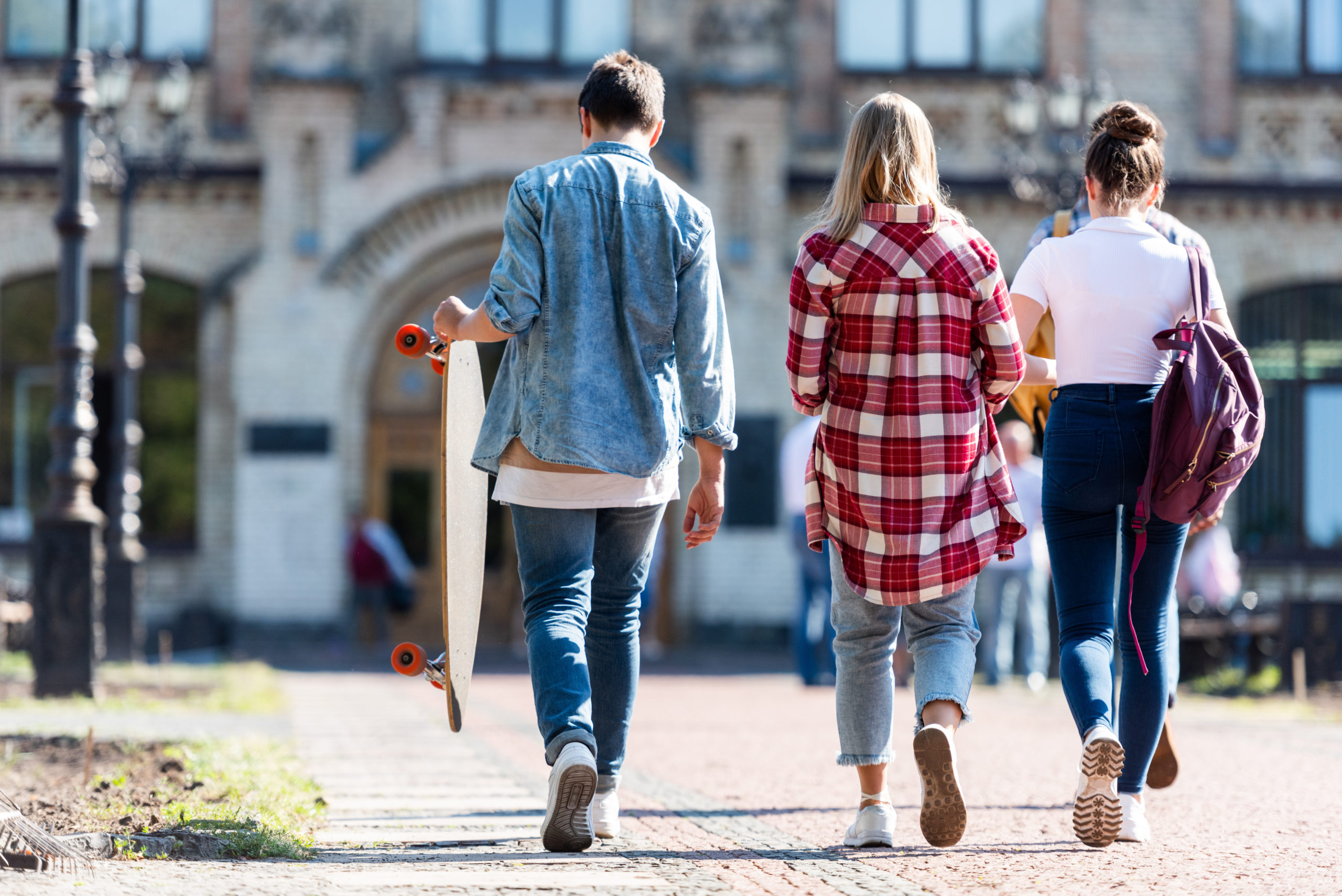 rear view of group of teen students walking in front of old college building