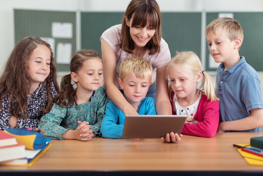 lehrerin zeigt kleinen kinder etwas am tablet